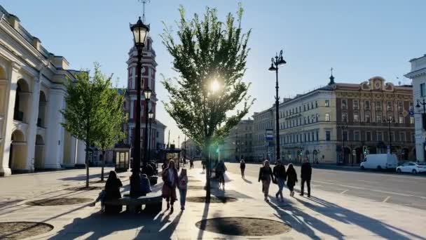 Rússia, São Petersburgo, 02 de junho de 2020: A arquitetura de Nevsky Prospect ao pôr do sol durante a pandemia do vírus Covid-19, Praça em frente ao pátio Gostiny, longas sombras de pessoas e carros — Vídeo de Stock