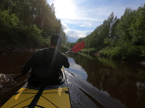 头戴礼帽的人在林间宁静的河边的皮划艇上漂浮着，美丽的风景，多变的天气，划着桨，映衬着美丽的倒影 — 图库照片