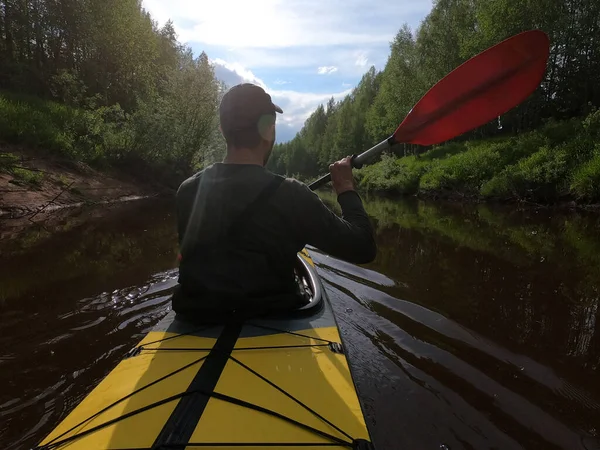 The men in a cap floats on a kayak on the forest quiet river, the beautiful landscape, a changeable weather, actively rows with an oar, beautiful reflection — Stock Photo, Image