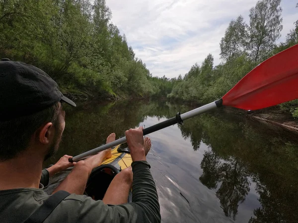 Los hombres en una gorra flota en un kayak en el bosque río tranquilo, el hermoso paisaje, un clima cambiante, reman activamente con un remo, hermoso reflejo —  Fotos de Stock