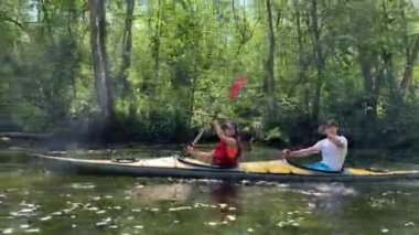 Rusya, Gatchina, 07 Haziran 2020: Bir çift ormanda bir kano üzerinde yüzüyor, güzel bir manzara, sakin bir nehir, güneşli bir hava, aktif bir kürek, güzel bir yansıma, gün ışığı