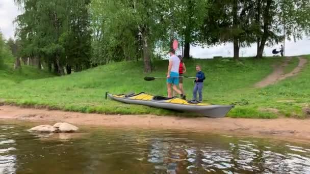 Ryssland, Gatchina, 07 juni 2020: Par sänker en kajak på vattnet i floden i skogen, det vackra landskapet, soligt väder, aktiva rader med en åra, vacker reflektion, solsken — Stockvideo
