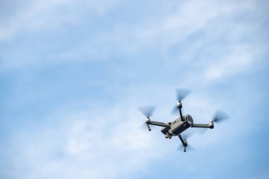 Gökyüzünde uçan dron, beyaz bulutlu mavi gökyüzü, güneşli hava, dönen pervaneler, hiç kimse
