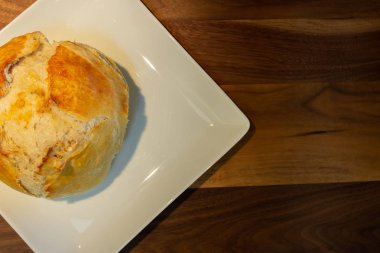 Kesme tahtası üzerinde beyaz bir tabak üzerinde taze yapılmış ekmek havai görünümü