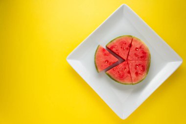 Sarı arka plan üzerinde beyaz bir tabak üzerinde Dilimlenmiş karpuz üst görünümü