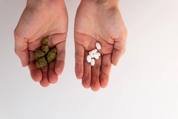 Традиционные против естественных. Руки держат таблетки и марихуану в разных руках . — стоковое фото