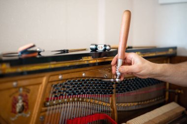 Teknisyen, piyanoyu akort ediyor. Piyano akustik bir piyanonun tellerinin gerilimini ayarlama eylemidir, böylece teller arasındaki müzik aralıkları akortludur..
