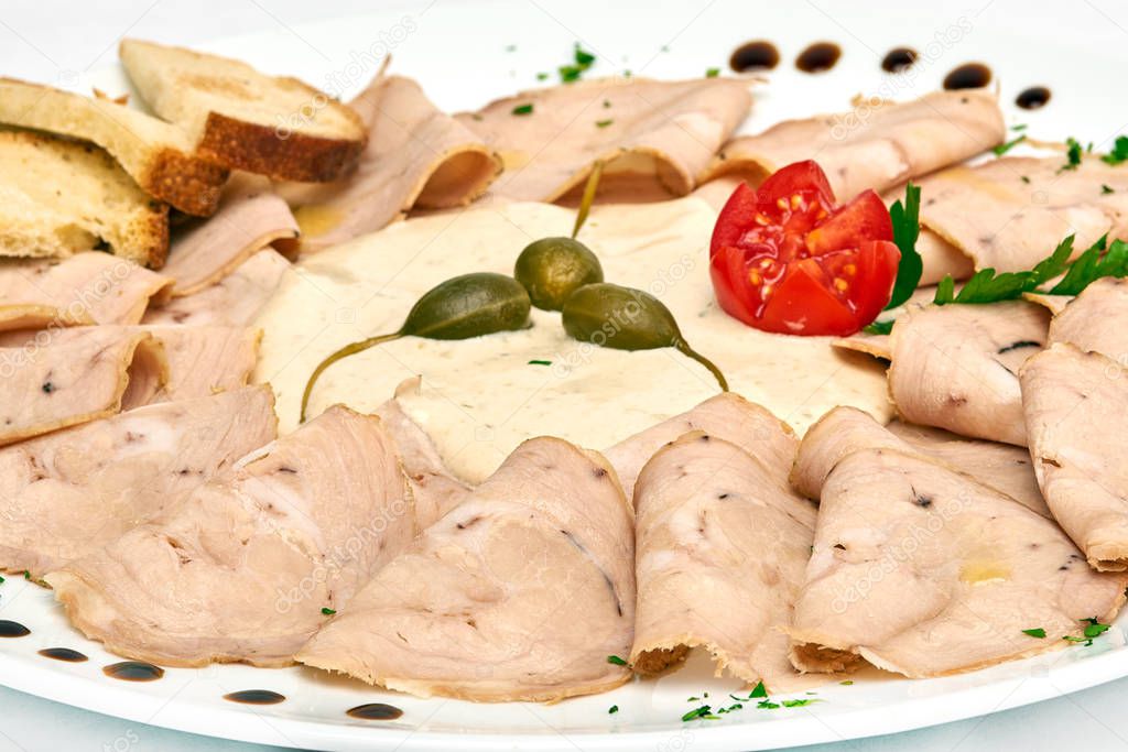 Vitello tonnato classic italian appertizer with veal and fish, served on white plate, isolated on white background
