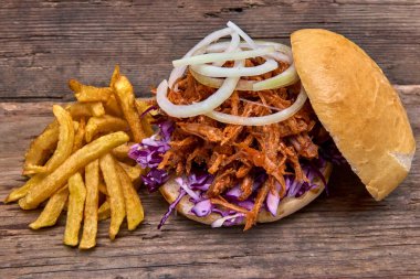 Barbekü çekti domuz sandviç ile barbekü sosu, kırmızı cabbageonion, sos ve patates salatası ahşap arka plan, Fast food