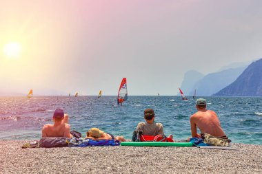 Bir Riva del Garda, Lago di Garda, İtalya - 21 Haziran 2018: banyo ve Lake Garda, güzel Garda Gölü yaz aylarında dağlarla çevrili, tan için sahilde oturup insanlar
