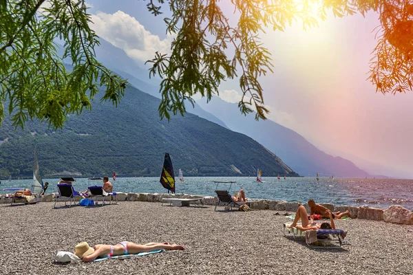 リーヴァ ガルダ ガルダ湖 イタリア 2018 日光浴 夏に山に囲まれた美しいガルダ湖のガルダ湖にビーチの上に座る人 — ストック写真