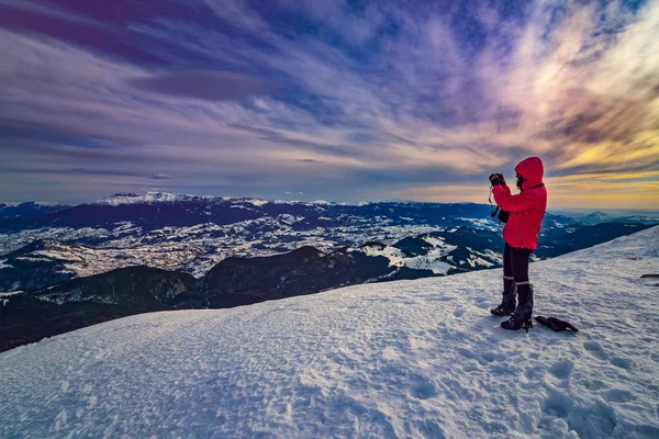 young woman taking pictures during winter time at sunset