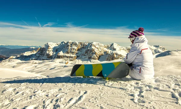 Snowboard oturan kızla top ve kayak tesisi Madonna di Campiglio manzaralarına hayran kalacaksınız