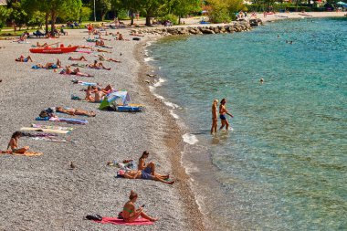 Torbole, İtalya-09 Ekim 2018: insanlar plajda şezlong üzerinde oturan ve yaz saati, görünümü dağlarla çevrili güzel Lake Garda Garda Gölü hayran