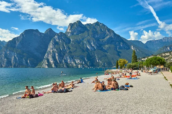 Torbole, İtalya-09 Ekim 2018: insanlar plajda şezlong üzerinde oturan ve yaz saati, görünümü dağlarla çevrili güzel Lake Garda Garda Gölü hayran