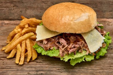 Barbekü çekti domuz sandviç yeşil salata, karamelize soğan, peynir, sos ve kişiler üzerine ahşap arka plan, Fast food