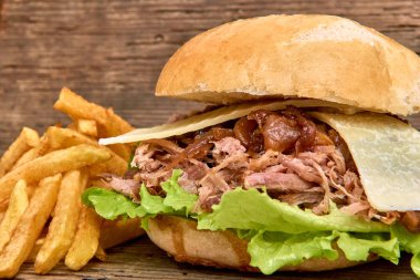 Barbekü çekti domuz sandviç yeşil salata, karamelize soğan, peynir, sos ve kişiler üzerine ahşap arka plan, Fast food