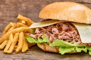 Barbekü çekti domuz sandviç yeşil salata, karamelize soğan, peynir, sos ve kişiler üzerine ahşap arka plan, Fast food