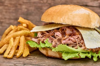 Barbekü çekti domuz sandviç yeşil salata, karamelize soğan, peynir, sos ve kişiler üzerine ahşap arka plan, Fast food