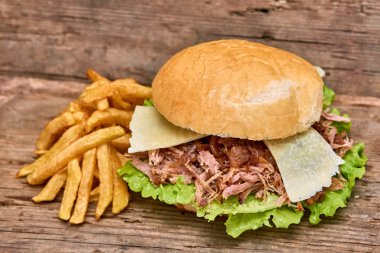 Barbekü çekti domuz sandviç yeşil salata, karamelize soğan, peynir, sos ve kişiler üzerine ahşap arka plan, Fast food