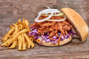 Barbekü çekti domuz sandviç ile barbekü sosu, kırmızı cabbageonion, sos ve patates salatası ahşap arka plan, Fast food