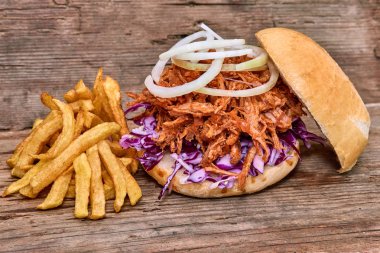Barbekü çekti domuz sandviç ile barbekü sosu, kırmızı cabbageonion, sos ve patates salatası ahşap arka plan, Fast food