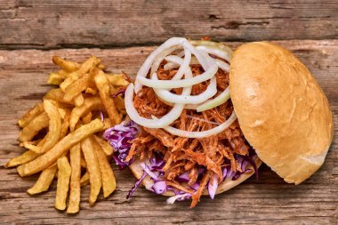 Barbekü çekti domuz sandviç ile barbekü sosu, kırmızı cabbageonion, sos ve patates salatası ahşap arka plan, Fast food