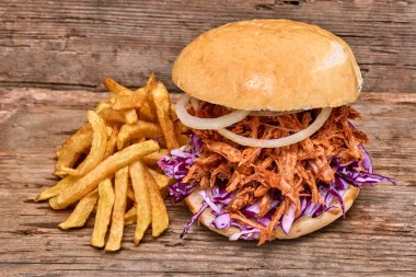 Barbekü çekti domuz sandviç ile barbekü sosu, kırmızı cabbageonion, sos ve patates salatası ahşap arka plan, Fast food