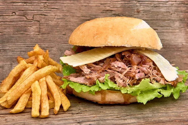 Barbeque Pulled pork Sandwich with green salad,caramelized onion,cheese,Sauce and Fries on wooden background,Fast food