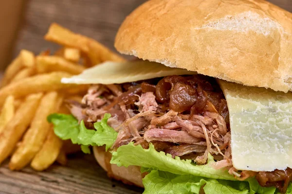 Barbeque Pulled pork Sandwich with green salad,caramelized onion,cheese,Sauce and Fries on wooden background,Fast food