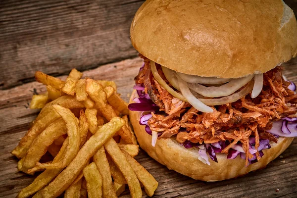 Barbeque Pulled pork Sandwich with BBQ Sauce,salad with red cabbageonion,Sauce and Fries on wooden background,Fast food