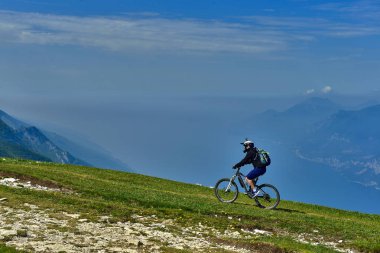 Monte Baldo, Lago di Garda, İtalya - 27 Mayıs 2016 dağ bisikleti adamı dağlar orman manzara yaz aylarında bisiklete binmek üzerinde. MTB dağ bisikletçinin Garda Gölü görünüme sahiptir