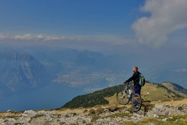 Monte Baldo, Lago di Garda, İtalya - 27 Mayıs 2016 dağ bisikleti adamı dağlar orman manzara yaz aylarında bisiklete binmek üzerinde. MTB dağ bisikletçinin Garda Gölü görünüme sahiptir
