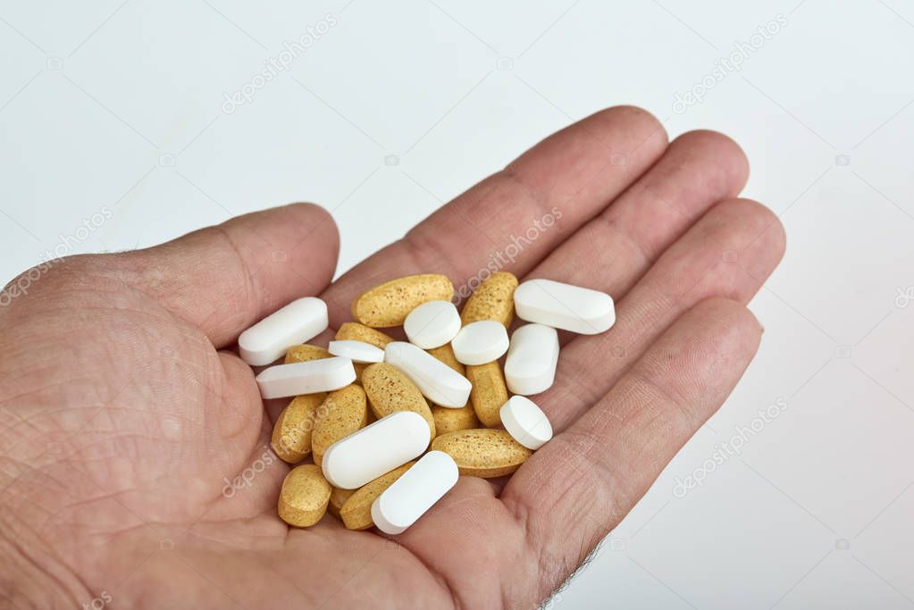 The hand of a man with different types of medication, Medicine pills or capsules in hand, palm. Colorful pills and medicines in the hand