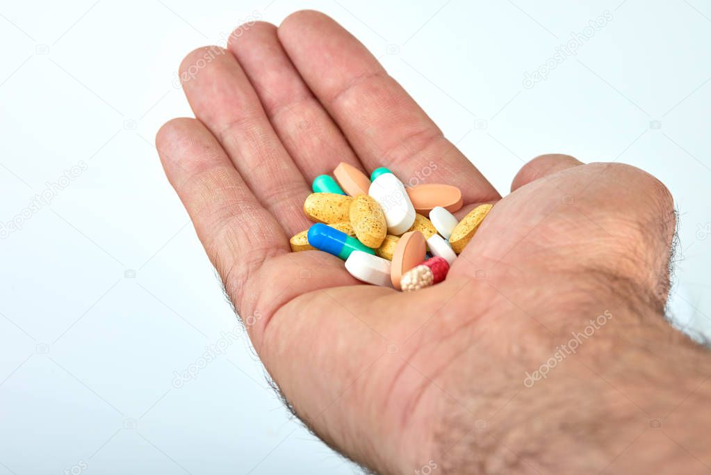 The hand of a man with different types of medication, Medicine pills or capsules in hand, palm. Colorful pills and medicines in the hand