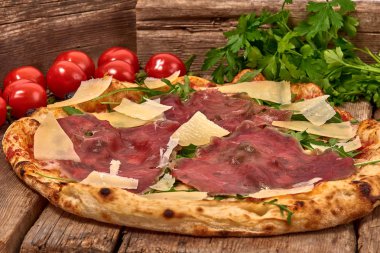 Ev yapımı taze lezzetli gurme pizza whit carpaccio sığır eti olgunlaştı, roket ve grana dilim peynir, ahşap masa, yakın seçici odak ile izole lezzetli İtalyan pizza