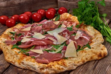 Ev yapımı taze lezzetli gurme pizza whit grana peynir, ham ham ve roket, ahşap masa, yakın seçici odak ile izole lezzetli İtalyan pizza