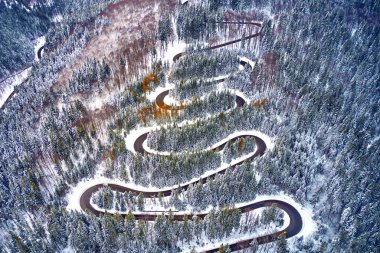 Yüksek dağ dolambaçlı yoldan hava görünümünü geçmek karla kaplı ağaçlar Transilvanya, Romanya, dron kış zamanında kavisli yol manzarası ile