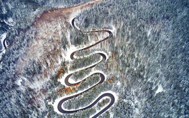 Yüksek dağ dolambaçlı yoldan hava görünümünü geçmek karla kaplı ağaçlar Transilvanya, Romanya, dron kış zamanında kavisli yol manzarası ile