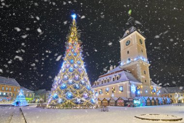 Brasov, Romania- 06 January 2019:Christmas Tree in the old city center of Brasov in a snowing night,Panoramic view of the old town and  Council Square
