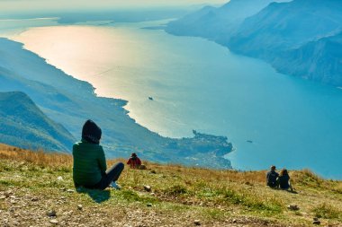 Monte Baldo'dan güzel Garda Gölü'ne hayran olan güzel bir kadın, dağlarla çevrili muhteşem Garda gölünün panoraması