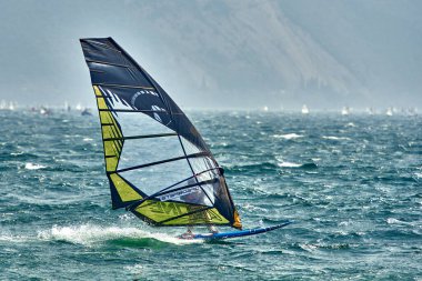 Riva del Garda, İtalya (Lago Benaco) - 14 Nisan 2017: Garda Gölü 'nde yüksek hızda sörf yapan rüzgar sörfçüsü