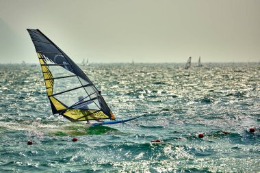 Riva del Garda, İtalya (Lago Benaco) - 14 Nisan 2017: Garda Gölü 'nde yüksek hızda sörf yapan rüzgar sörfçüsü