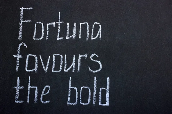 Lettering on a dark blackboard in white chalk fortuna favored the bold