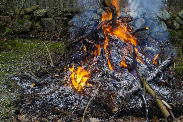 Burning a pile of garden waste in a residential countryside garden. A fire with yellow and orange flames, ash and smoke.