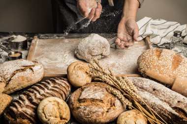 Baker'ın elleri pasta kurulu üzerinde çiğ hamur un serpin. Bütün tahıl somun ekmek - küçük fırın sahne yapma. 