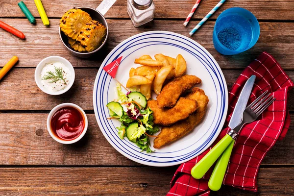 Comida para niños - tiras de pollo, papas fritas, ensalada, maíz y salsas — Foto de Stock