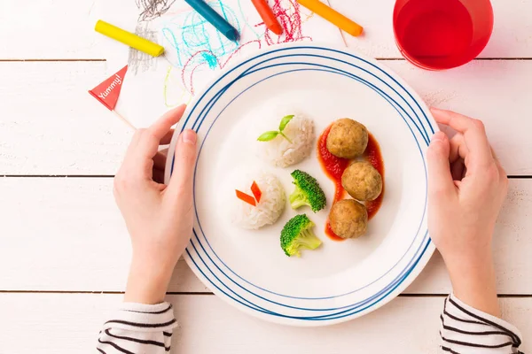 Питание (ужин) в руках ребенка - фрикадельки, рис, брокколи — стоковое фото