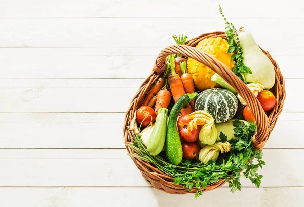 Légumes bio colorés dans un panier en osier sur bois blanc — Photo