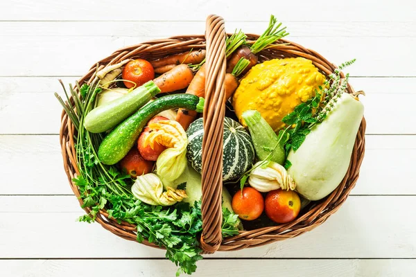 Légumes bio colorés dans un panier en osier sur bois blanc — Photo